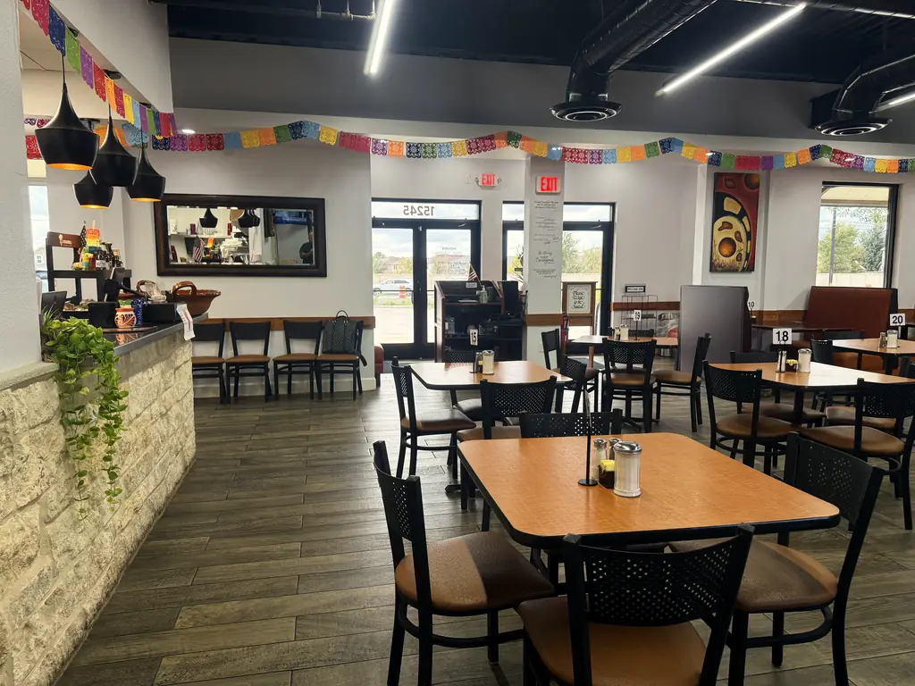The dining room under papel picado and black pendant lamps